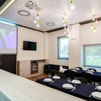Comedor con cubertería, vajilla y proyector, desde la cocina