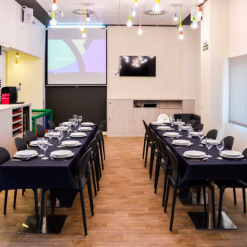 Comedor con cubertería, vajilla, proyector y cocina abierta